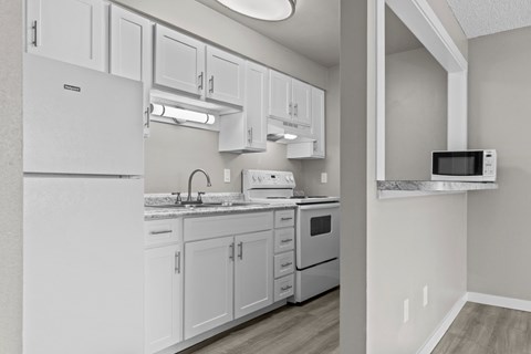 A kitchen with white cabinets and appliances.
